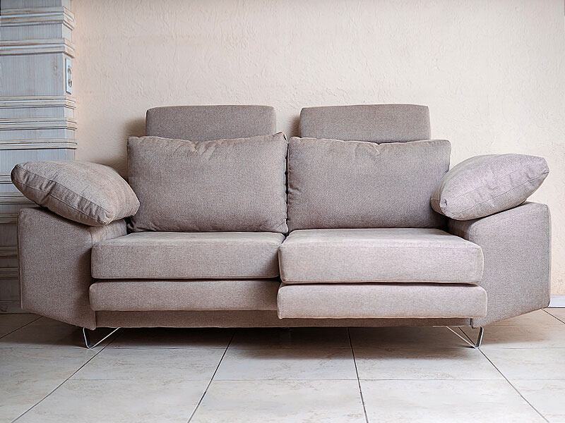 Sofá gris de diseño moderno con líneas rectas, cojines integrados y patas metálicas delgadas